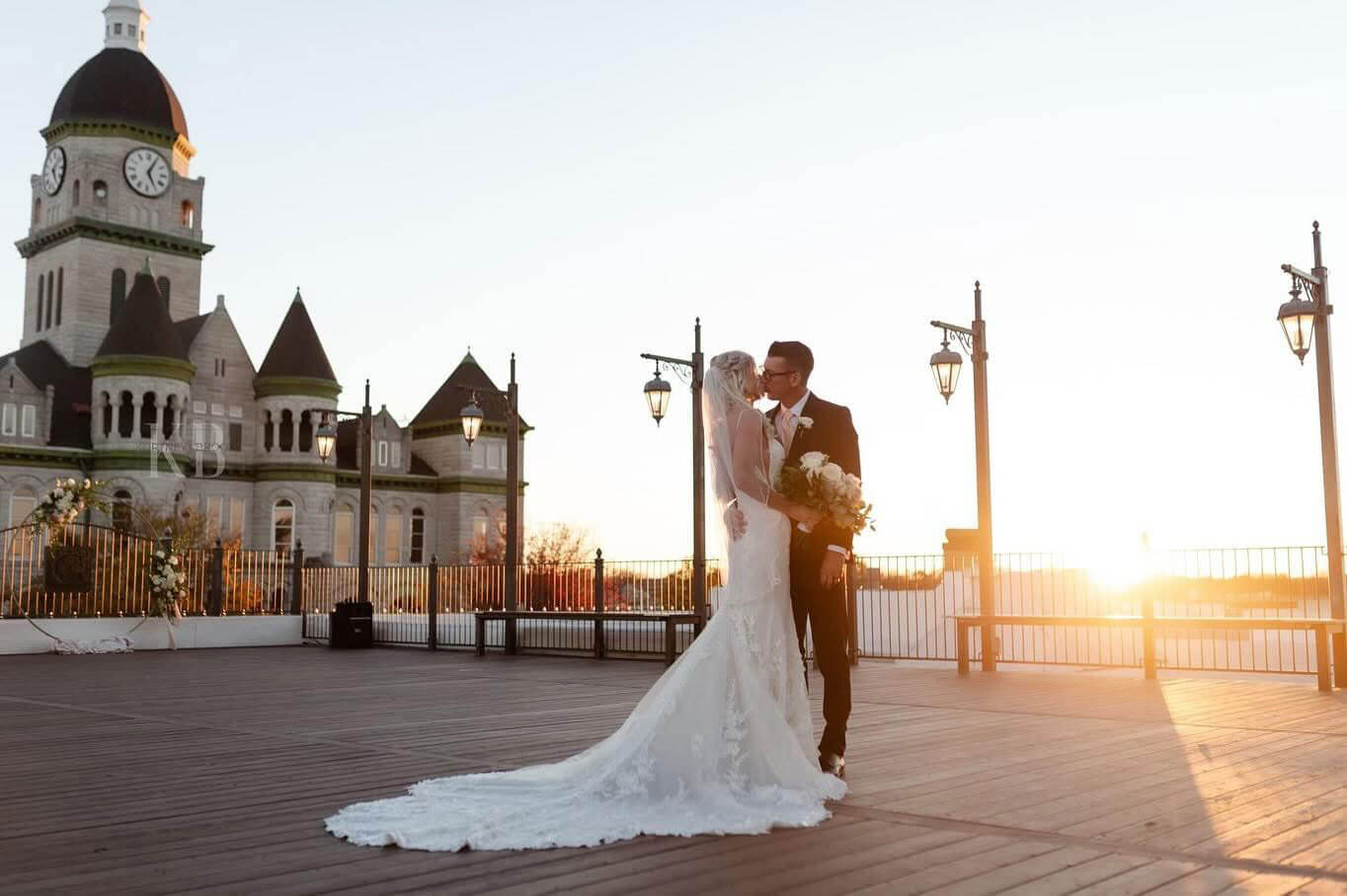 Bride and groom kissing on the rooftop at sunset with the courthouse behind